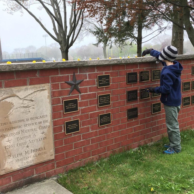 A child touches the veteran plaques at the Armory Park memorial